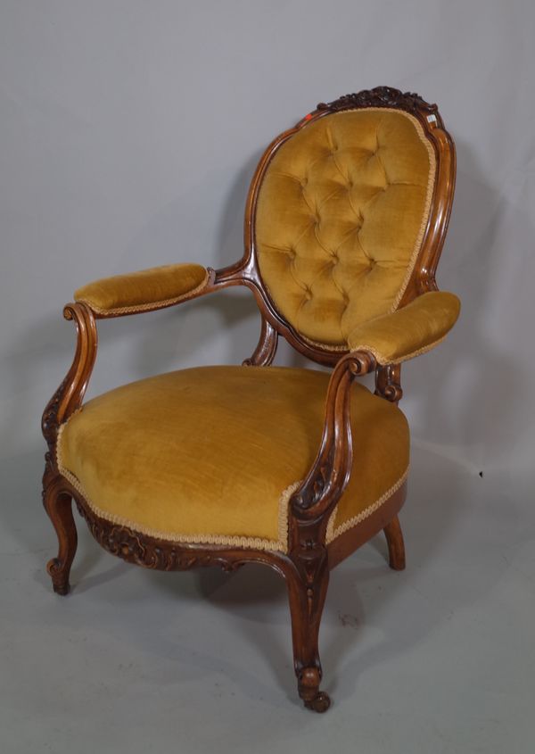 A Victorian mahogany framed open armchair with button back green upholstery on cabriole supports.