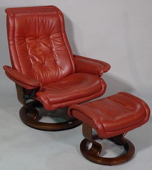A contemporary swivel back leather upholstered easy chair, with matching footstool, (2).