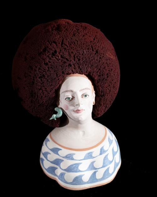 A 21st century stylised pottery bust of a woman, with serpent earrings and natural sea sponge hair, (a.f.), indistinctly signed Pa***nope 2004, 19cm h