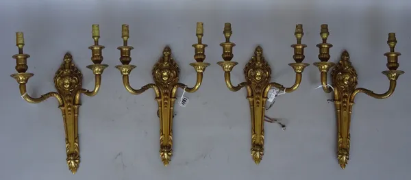 A set of four Louis XVI style gilt brass two branch wall appliques, early 20th century, each relief cast with cherub portrait mask, backplate 33cm. (4