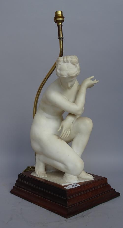 An alabaster figural table lamp, late 19th century, depicting a crouching Venus on a later oak plinth, Venus 36cm high.