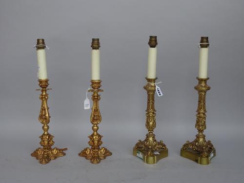 A pair of modern gilt metal table lamps of 18th century 'candlestick' form raised on a triform base, 28cm high and a similar pair of gilt metal candle