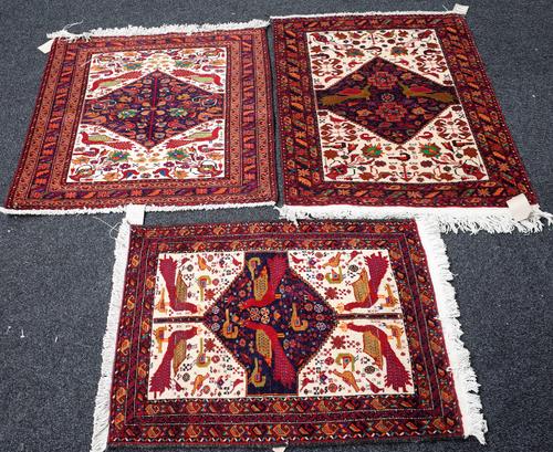 Three Baluchistan mats, each with indigo diamond filled with peacocks, other birds and flowers, 84cm x 66cm, 89cm x 83cm and 95cm x 77cm, (3).