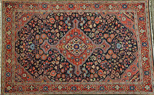 A Bidjar rug, Persian, the dark indigo floral field with a bold madder and ivory medallion, matching spandrels, a madder rosette and vine border, 203c
