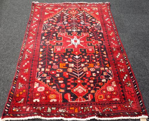 A Hamadan rug, Persian, the black field with a madder medallion, spandrels and angular sprays, a madder border, 213cm x 131cm and a North West Persian