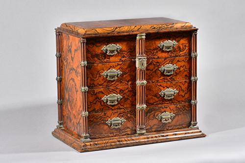 A Victorian Gothic Revival walnut and faux figured walnut table top cabinet with two rows of four fully veneered drawers on coromandel runners enclose