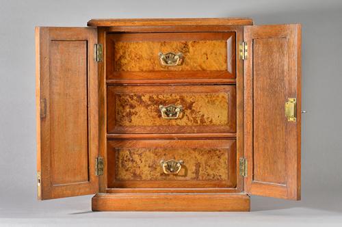 A Victorian oak table top cabinet, the pair of panel doors enclosing three figured walnut drawers, 37cm wide x 43cm high.