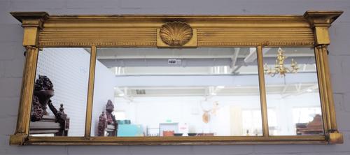 An early Regency gilt framed triple plate overmantel mirror with shell moulded frieze and cluster column mounts, 133cm wide x 51cm high.