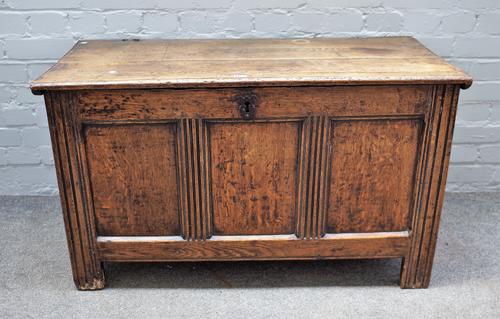 A 17th century oak coffer, the plank top over triple panel front on stile feet, 104cm wide x 61cm high.