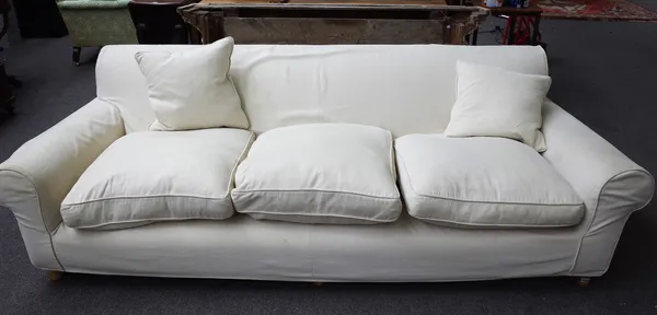 A modern three seat sofa, with cream loose covers, on turned beech supports, 225cm wide x 70cm high.