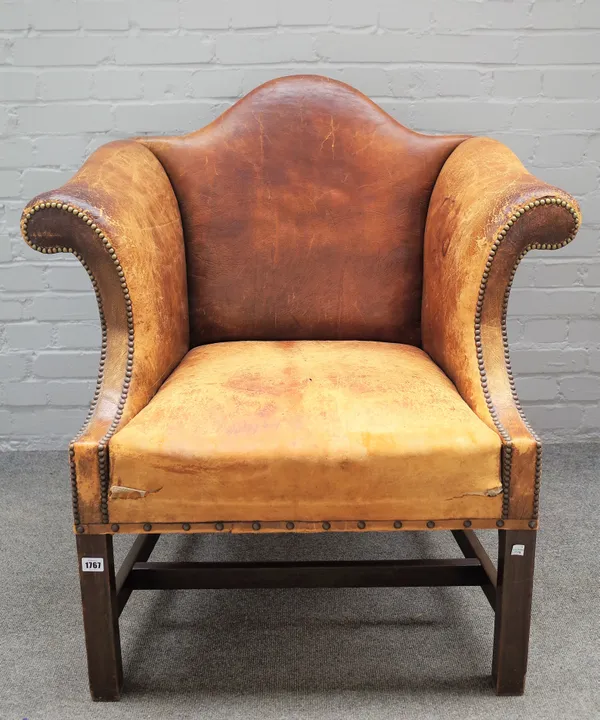 A George II style brown leather upholstered low hump back armchair with outswept arms and block supports, 90cm wide x 94cm high.