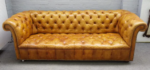 A 20th century studded tan leather upholstered button back Chesterfield sofa on bun feet, 228cm wide x 77cm high.