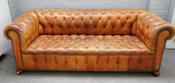 A 20th century studded tan leather upholstered button back Chesterfield sofa on bun feet, 214cm wide x 77cm high.