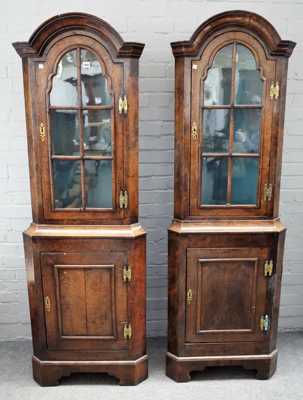 A pair of 18th century style figured walnut corner display cabinet/cupboards, the bonnet top over single glazed door and panelled lower door, on brack