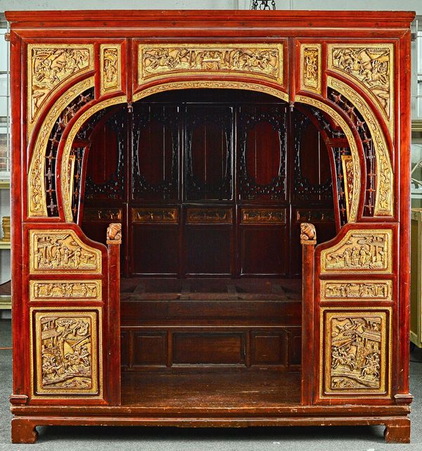 A late 19th century Chinese red lacquer parcel gilt opium bed with rounded entrance and panel interior, 212cm wide x 225cm high x 233cm deep.