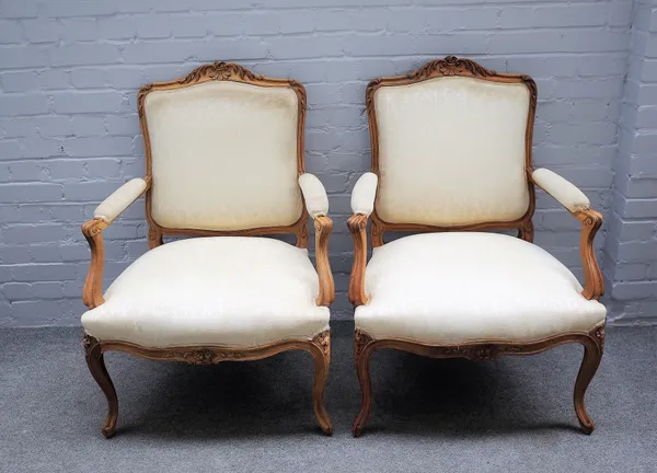 A pair of Louis XV style walnut framed open armchairs, with carved crest rail and serpentine seat on cabriole supports, 70cm wide x 98cm high, (2).