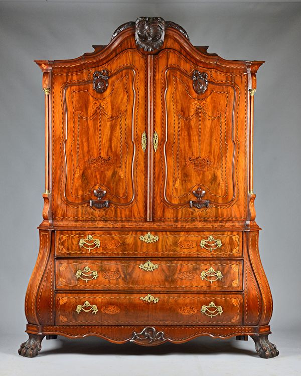 A late 18th century Dutch marquetry inlaid Armoire, the shell carved bonnet top over a pair of shaped panel doors, the bombe base with three long grad