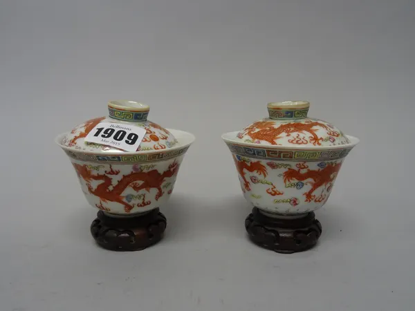 A pair of Chinese famille-rose cups and covers, late 19th/20th century, each piece painted with two iron-red dragons chasing a flaming pearl, four-cha