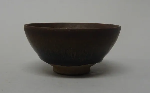 A Chinese `hare's fur' pottery teabowl, Song dynasty style but probably later, covered inside and out with a streaked cinnamon to dark brown glaze, 9c