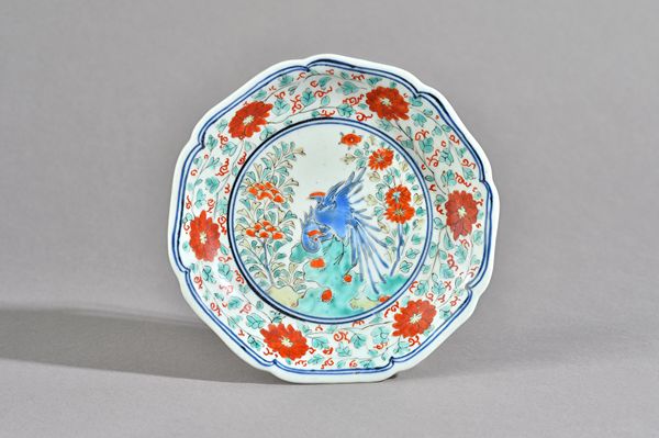 A small Japanese kakiemon lobed dish, Edo period, late 17th century, enamelled in the centre with two birds on rocks flanked by flowers, inside a bord