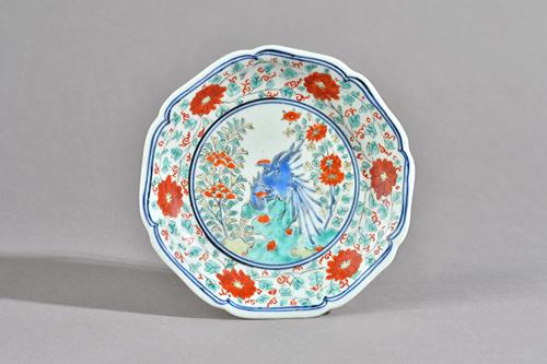 A small Japanese kakiemon lobed dish, Edo period, late 17th century, enamelled in the centre with two birds on rocks flanked by flowers, inside a bord