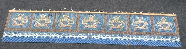 A long Chinese embroidered blue-ground border hanging, 19th century, worked with seven panels of dragons inside key pattern borders above waves, appro