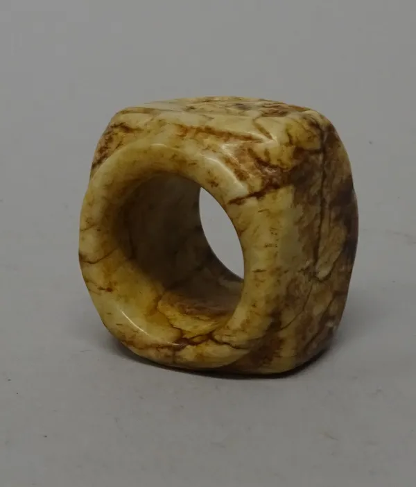 A Chinese cream and brown jade cong, probably 4th century B.C, rounded square form with tubular centre, carved on one side of the exterior with  mythi