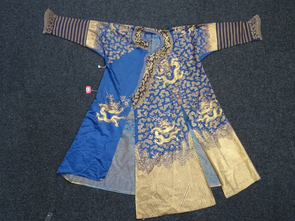 A Chinese embroidered blue- ground dragon robe, 19th century, worked with dragons amongst cloud scrolls in gilt thread above waves.