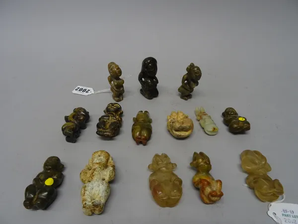 A group of twelve jade and two rock crystal figures, various colours, mostly carved in a squatting pose, sizes 5cm. to 7cm., (14).