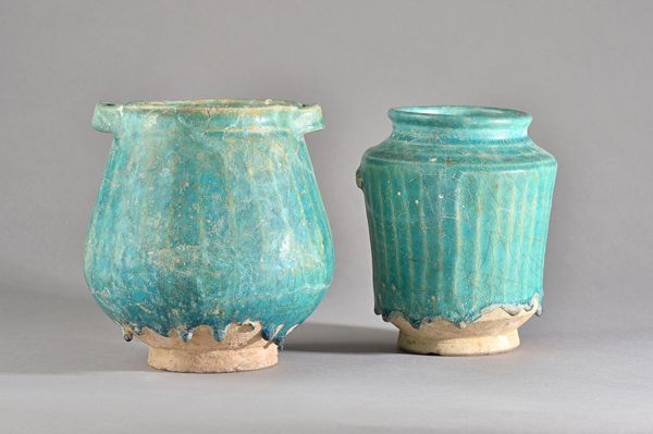 Two Kashan turquoise glazed pottery vessels, Persia, circa 12th century, comprising; a jar with lug handles and a waisted cylindrical albarello, each