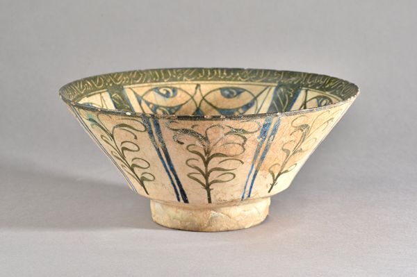 A Kashan pottery bowl, Persia, 13th century, with straight flared sides, the inside painted with radiating arabesque and calligraphic decoration in bl