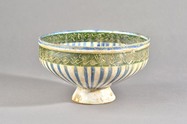 A Kashan pottery bowl, Persia, 13th century, with radiating blue painted decoration to the interior and exterior, black-ground calligraphic bans aroun