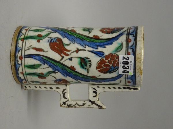 An Iznik pottery cylindrical tankard, Ottoman Anatolia, first half 17th century, the sides painted with tulip, rose and saz leaf motifs, the handle wi