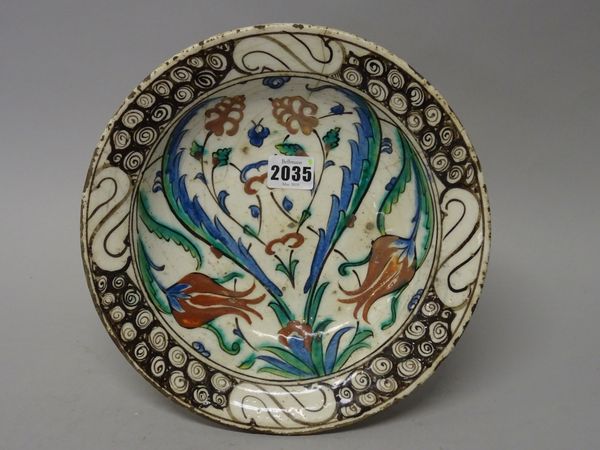 An Iznik pottery dish, Ottoman Anatolia, first half 17th century, painted with polychrome tuilp, lily and saz leaf decoration, the rim with `wave and