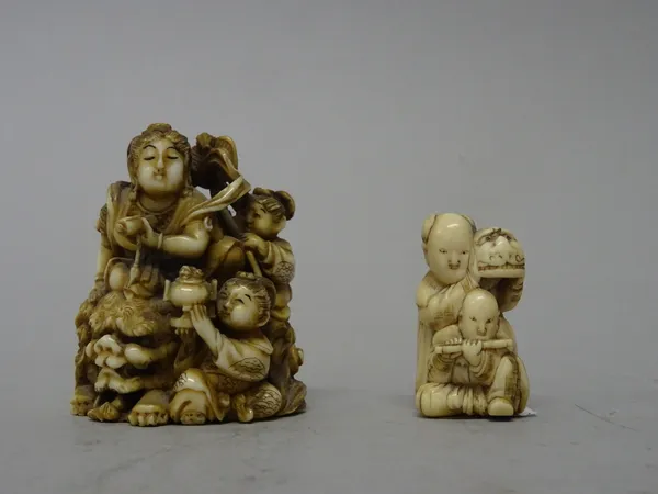 A Japanese ivory netsuke, Meiji period, carved as a woman seated on the back of a recumbent shishi, two young attendants at her side, signed, 6cm. hig