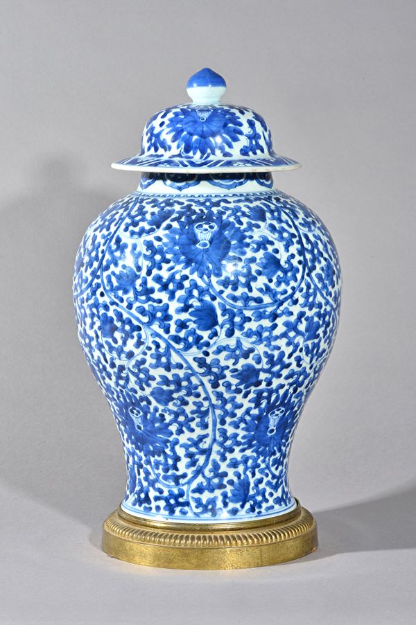 A Chinese blue and white baluster vase and a cover, Kangxi, painted with lotus flowers and leafy branches, 44cm. high, gilt-metal stand, (3).