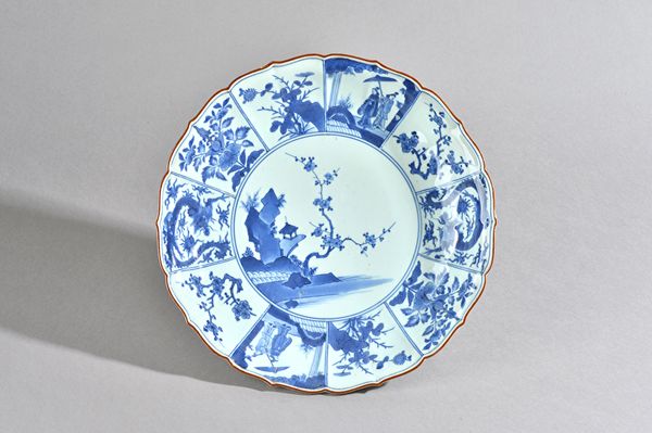 A Japanese blue and white kakiemon-style dish, Edo period, late 17th century,painted in the centre with a building on a rocky promontory, a pine tree