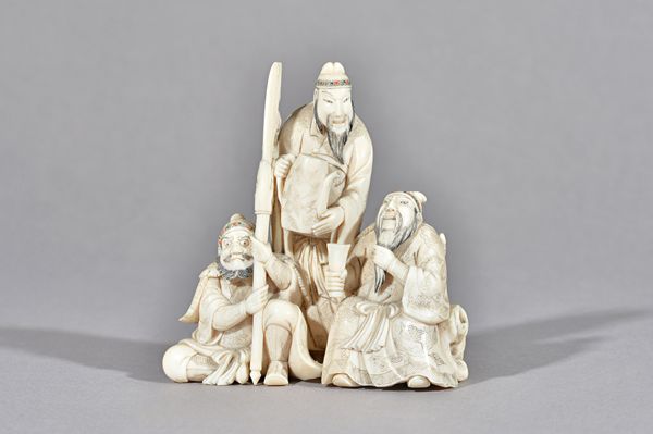 A Japanese ivory okimono, Meiji period, carved as a man standing about to pour tea to a seated official, a grimacing warrior seated beside holding a h