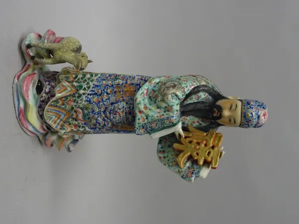 A Chinese porcelain famille-rose figure, 20th century, modelled as a bearded man wearing a colourful dragon robe, holding characters in both hands, a