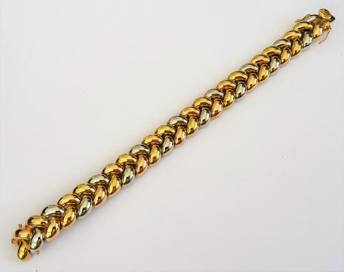 A two colour gold bracelet, in an interwoven herring bone link design, on a snap clasp, detailed Poiray 750 18 KT, length 18.3cm, weight 56 gms, with