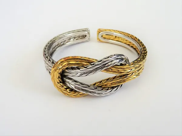 A two colour gold bangle, in an entwined ropetwist design, the front with a knot motif, detailed 750, weight 69.2 gms.