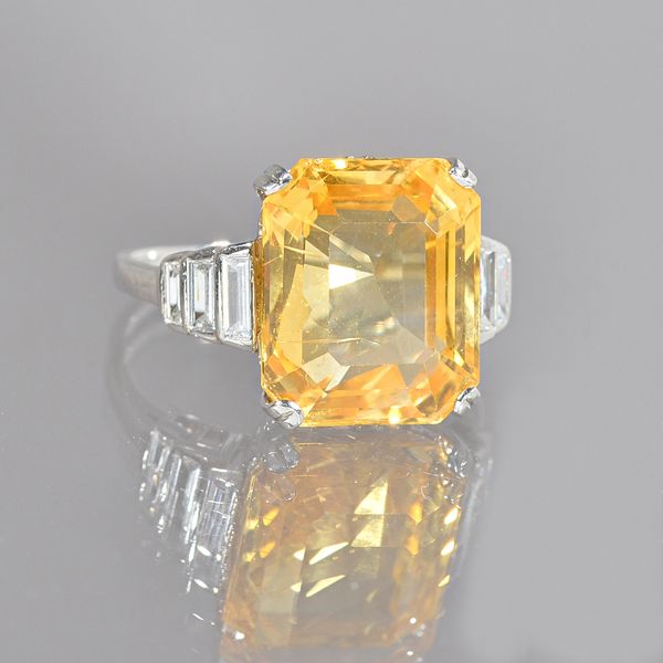 A yellow sapphire and diamond ring, the claw set cut cornered rectangular step-cut yellow sapphire mounted between baguette diamond three stone should