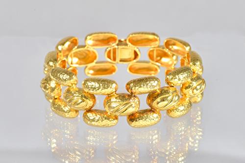 A gold bracelet, in a three row domed link design, with a partly martele finish, on a snap clasp, detailed 750, length 17.5cm, weight 54.2 gms.