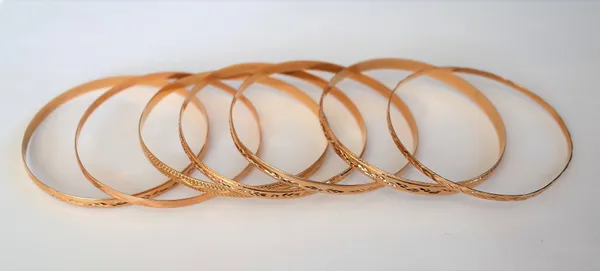 Seven 9ct gold circular bangles, in a variety of designs, with engraved decoration, combined weight 45.1 gms, (7).