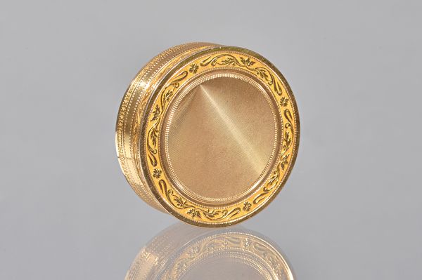 A French gold box and cover, of circular form, with engine turned decoration to the centre of the lid and to the base, within foliate scroll engraved