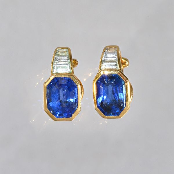 A pair of gold, sapphire and diamond earclips, each mounted with a cut cornered rectangular step cut sapphire and with a row of three tapered baguette