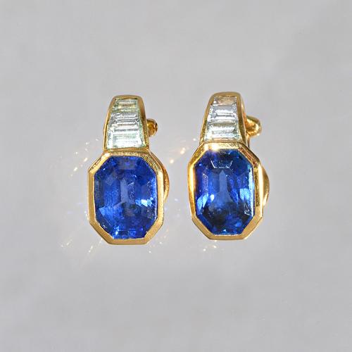 A pair of gold, sapphire and diamond earclips, each mounted with a cut cornered rectangular step cut sapphire and with a row of three tapered baguette
