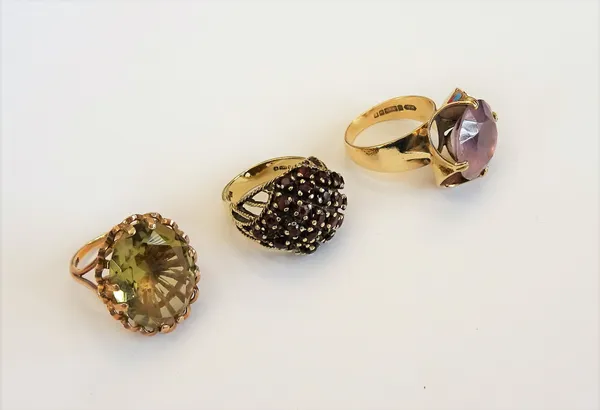 A 9ct gold ring, claw set with a circular cut amethyst, a 9ct gold ring, claw set with an oval cut citrine and a 9ct gold and garnet set cluster ring