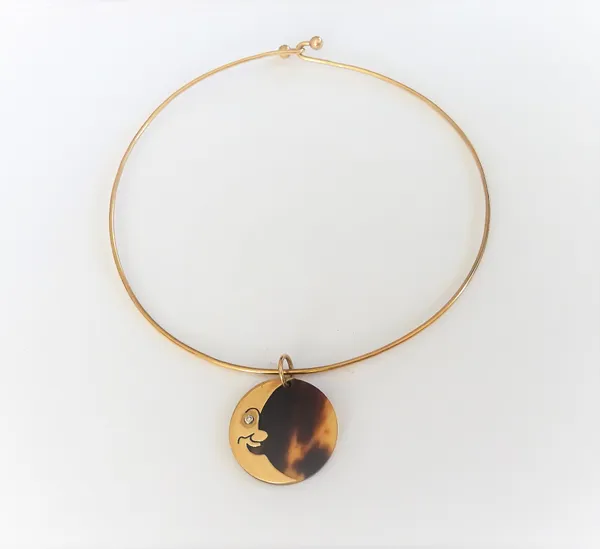 A gold, diamond set and tortoiseshell pendant, of circular form, designed as the face of a crescent moon, with a circular cut diamond mounted to the e