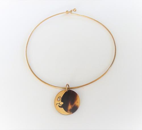 A gold, diamond set and tortoiseshell pendant, of circular form, designed as the face of a crescent moon, with a circular cut diamond mounted to the e